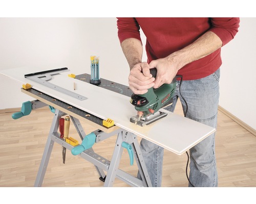 Osoba reže obrobok priamočiarou pílou na pracovnom stole.