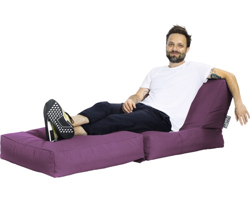 Muž relaxuje na fialovom sedacom ostrove s podnožkou.