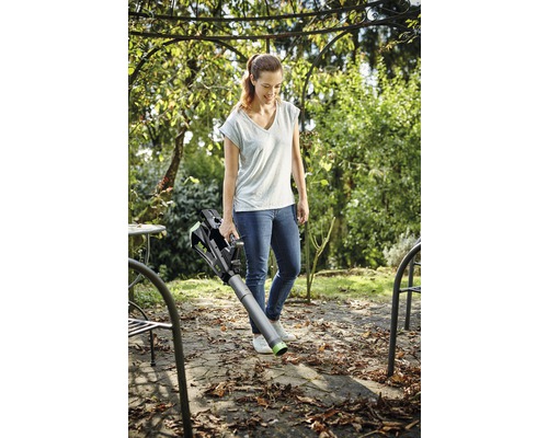 Žena používa fúkač lístia v záhrade na odstraňovanie lístia.