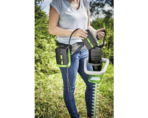 Žena vymieňa batériu na nožniciach na živý plot s akumulátorovým pásom