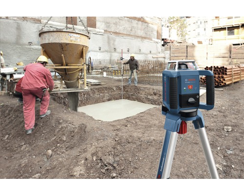 Rotačný laser na stavenisku s betonárskymi prácami a stavebnými robotníkmi