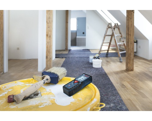 Renovácia miestnosti s laserovým diaľkomerom, farbou a štetcom na vedre