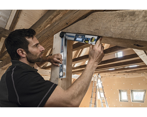 Remeselník používa digitálnu uhlomerku na drevenom tráme