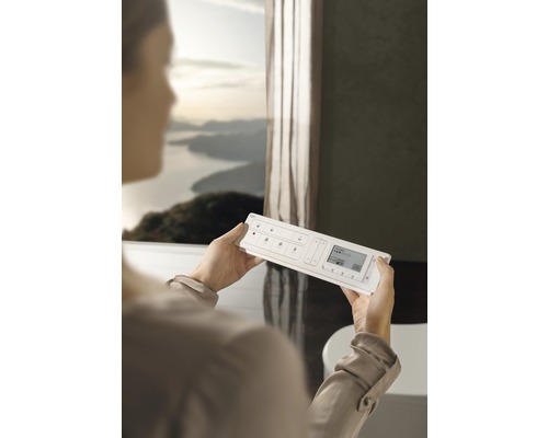 Žena drží systém domácej automatizácie v kúpeľni.