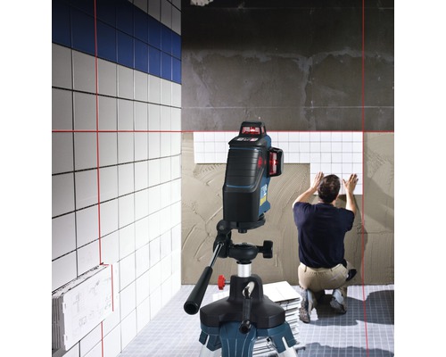 Scéna zobrazuje obkladača pracujúceho s líniovým laserom na vyrovnanie dlaždíc.