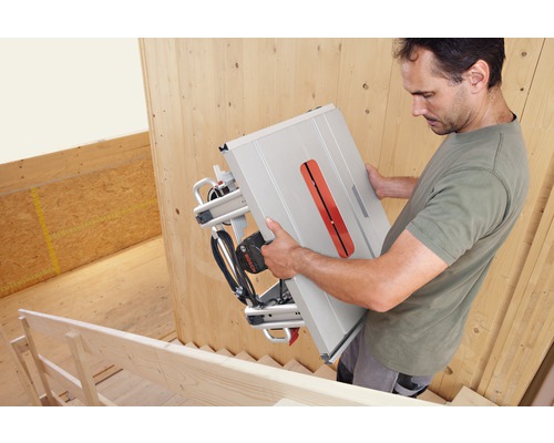 Muž nesie stolnú okružnú pílu Bosch po schodoch.