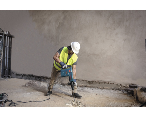 Stavebný robotník používa demolačné kladivo na úpravu podlahy.