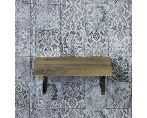 Drevená polica s kovovými držiakmi pred vzorovanou stenou