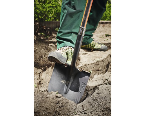 Osoba používa rýľ na kopanie v záhrade.