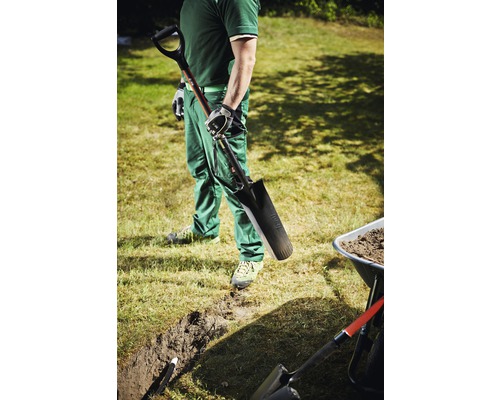 Muž s rýľom, priekopou a fúrikom v záhrade