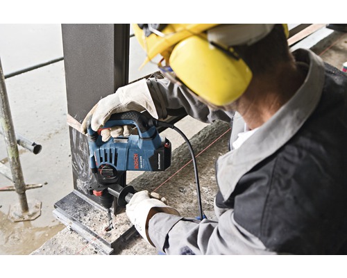 Robotník vŕta otvor do kovového nosníka pomocou vŕtačky Bosch GBH 3-28 F Professional.