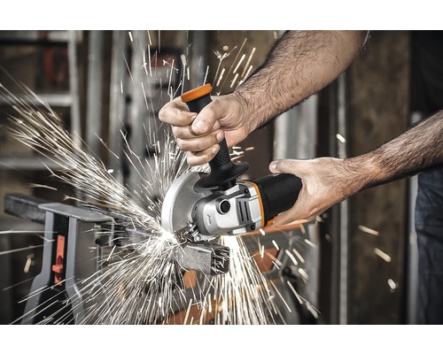 Osoba reže uhlovou brúskou kus kovu, pričom odletujú iskry.