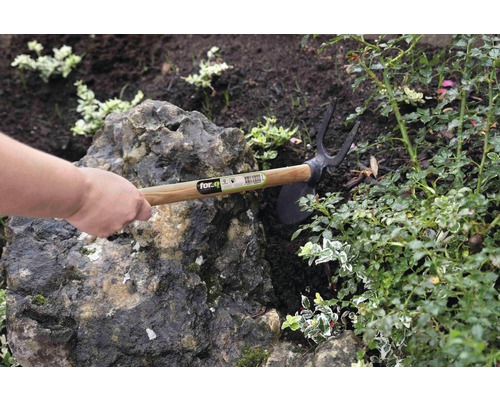 Záhradná motyka s drevenou rukoväťou používaná v záhradnom záhone.