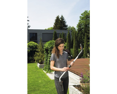 Žena drží akumulátorové nožnice na trávu v záhrade.