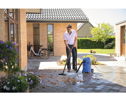 Muž čistí dlažbu vonku pomocou mokrého a suchého vysávača.