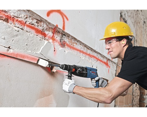 Stavebný robotník vŕta dieru do steny pomocou vŕtacieho kladiva.