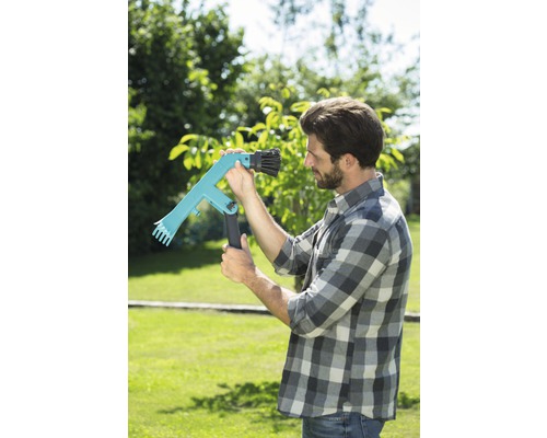 Muž v záhrade používa zberač ovocia na zber.