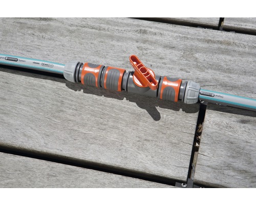 Regulačný ventil Gardena spojený so záhradnou hadicou na drevenom stole