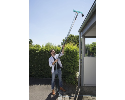 Muž čistí odkvap pomocou čističa odkvapov a teleskopickej tyče.