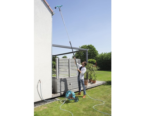 Muž čistí odkvap pomocou čističa odkvapov na teleskopickej tyči