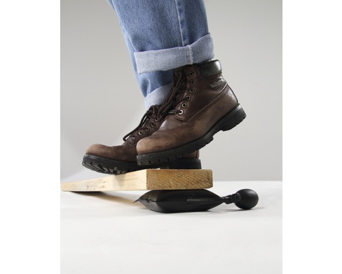 Osoba v topánkach balancuje na vzduchovom vankúši medzi kusmi dreva