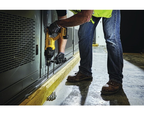 Muž vŕta vŕtačkou diery do steny.