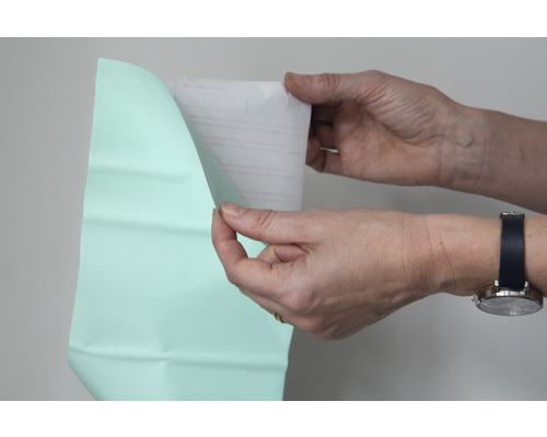 Osoba odstraňuje ochrannú fóliu z fólie.