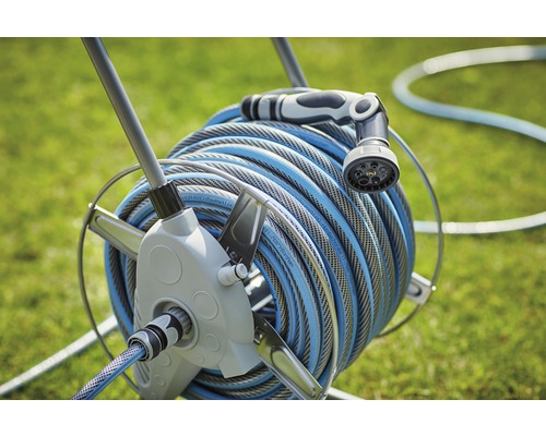 Navijak so záhradnou hadicou a striekacou tryskou v záhrade