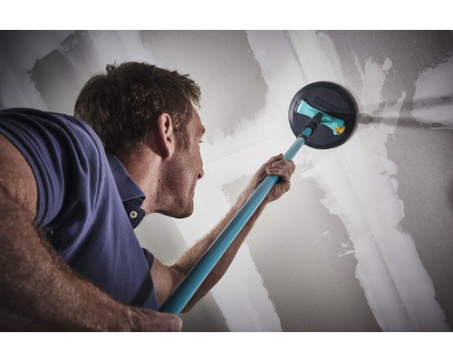 Muž brúsi stenu pomocou brúsky na sadrokartón pre renováciu