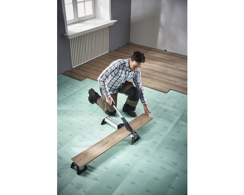 Muž reže laminát rezačkou laminátu na kročajovej izolácii