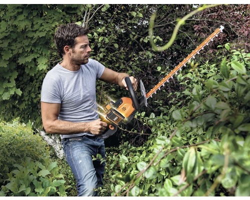 Muž strihá živý plot pomocou akumulátorových nožníc na živý plot