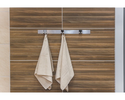 Pohľad na kúpeľňu s uterákmi na držiaku uterákov pred stenou s drevenými obkladmi