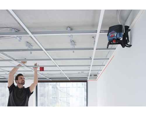 Muž montuje stropnú konštrukciu s líniovým laserom na vyrovnanie