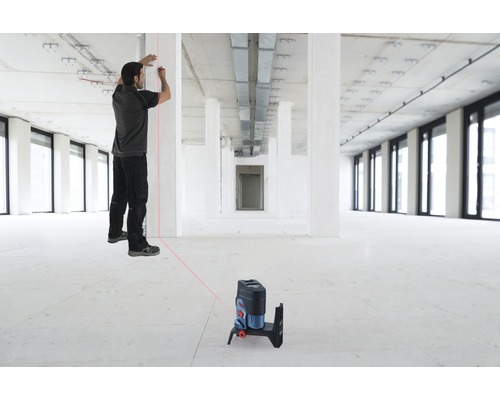 Muž pracuje s čiarovým laserom v hrubej stavbe na vyrovnanie.