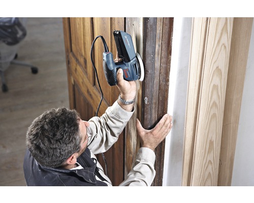 Muž brúsi drevený rám dverí multifunkčnou brúskou