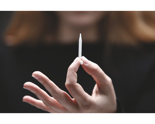 Ruka drží injektor.