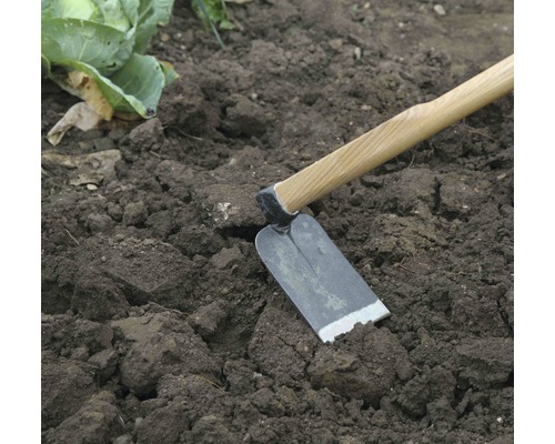 Motyka s drevenou násadou v záhradnej pôde