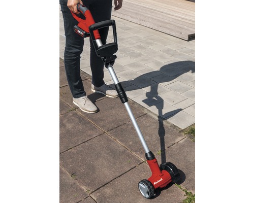 Osoba obsluhuje akumulátorový čistič škár na dlažobných kockách