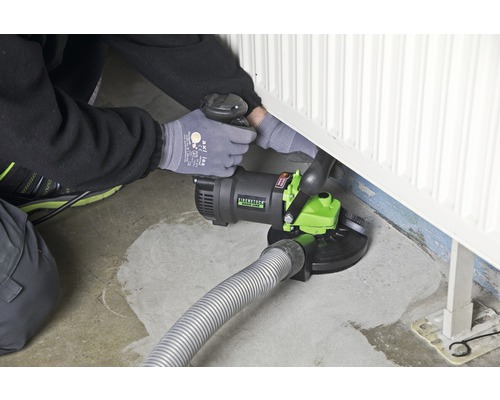 Muž používa frézu na renováciu betónu na radiátore na podlahe