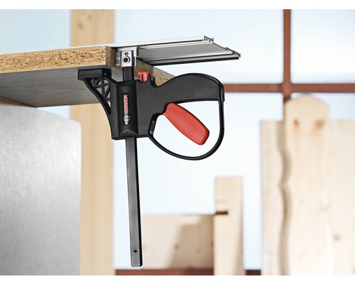 Logo Bosch. Obrobok pripevnený k vodiacej lište pomocou jednoručnej svorky Bosch.