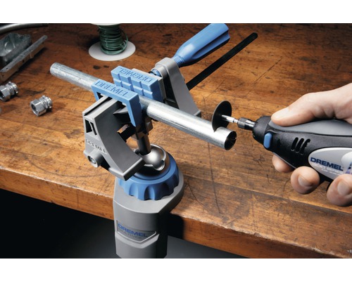 Logo spoločnosti Dremel. Pracovný stôl s multifunkčnými zverákmi Dremel a multifunkčným nástrojom Dremel na rezanie rúrky.