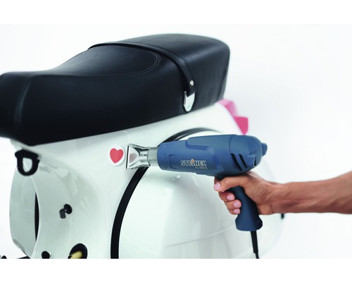 Teplovzdušná pištoľ pri nanášaní nálepky na skúter