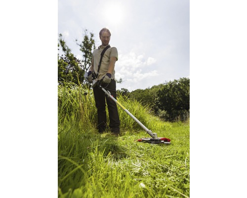 Muž pracuje so strunovou kosačkou na záhrade.