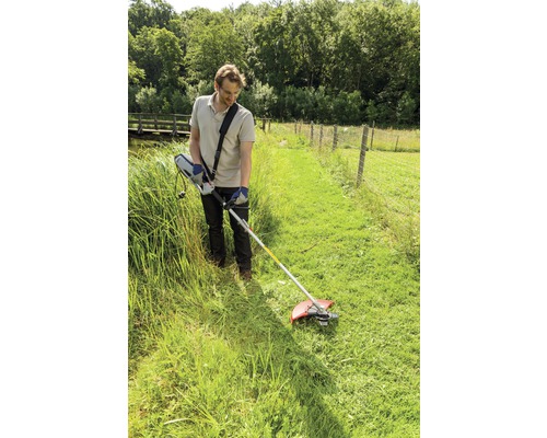 Muž pracuje so strunovou kosačkou na záhrade