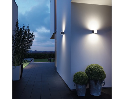 Exteriér domu s dvoma modernými nástennými svietidlami, ktoré osvetľujú fasádu