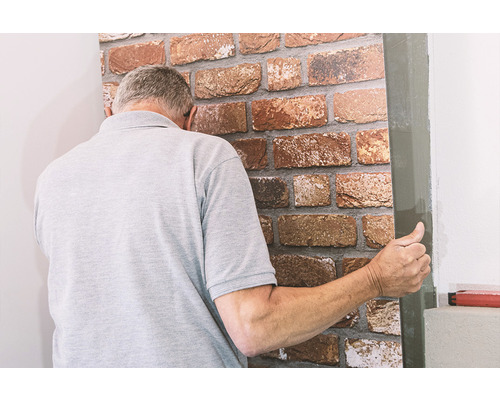 Muž inštaluje obklad steny s kamenným vzhľadom