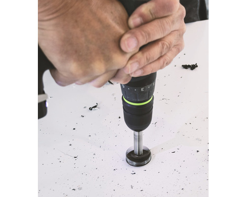 Osoba vŕta otvor do povrchu pomocou vŕtačky.