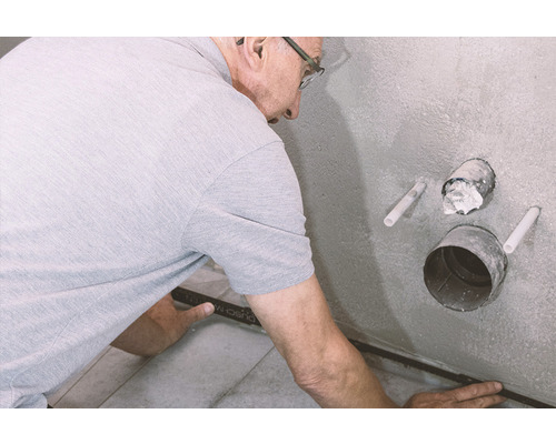 Muž pokladá obkladačskú lištu v kúpeľni.