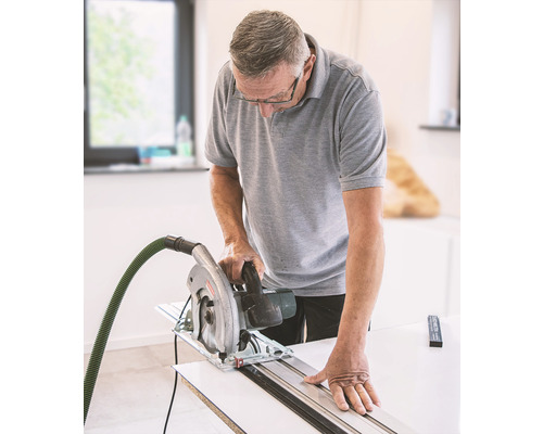 Muž reže drevo ručnou okružnou pílou a vodiacou lištou