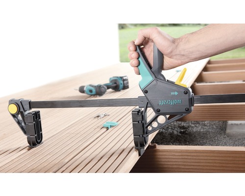 Jednoručná svorka Wolfcraft na drevenej terase pri použití s akumulátorovým skrutkovačom